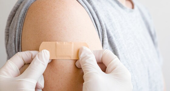 A picture of a practitioner placing a band aid on a patient’s arm A picture of a practitioner placing a band aid on a patient’s arm