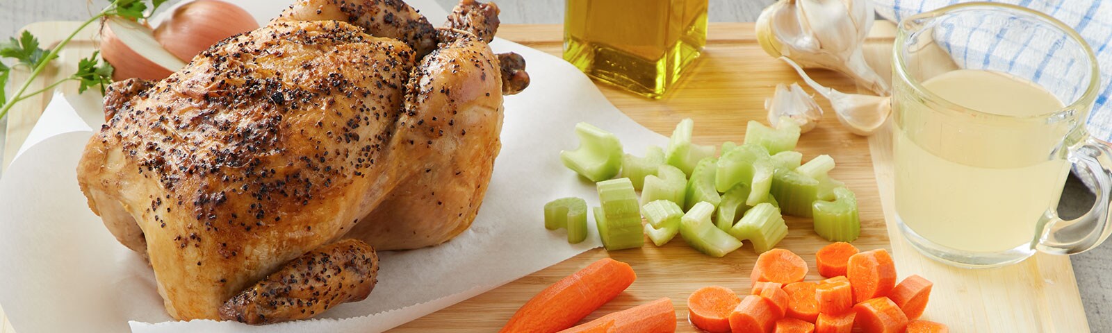 Whole cooked chicken with chopped carrots and celery on a table