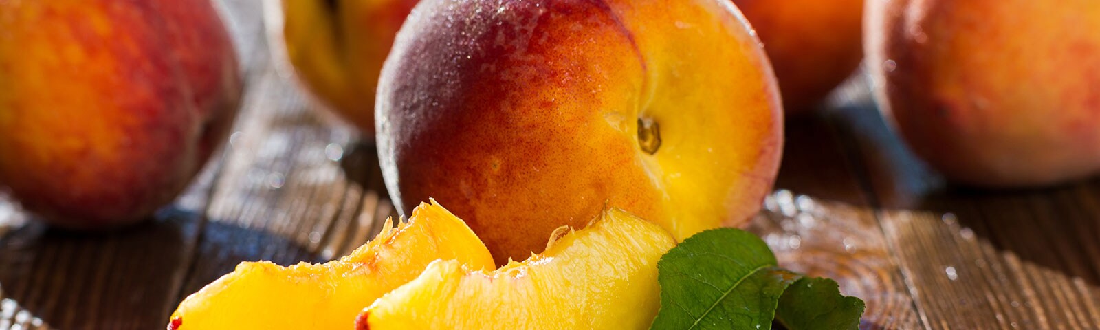 Multiple peaches on wooden table with green leaves Multiple peaches on wooden table with green leaves
