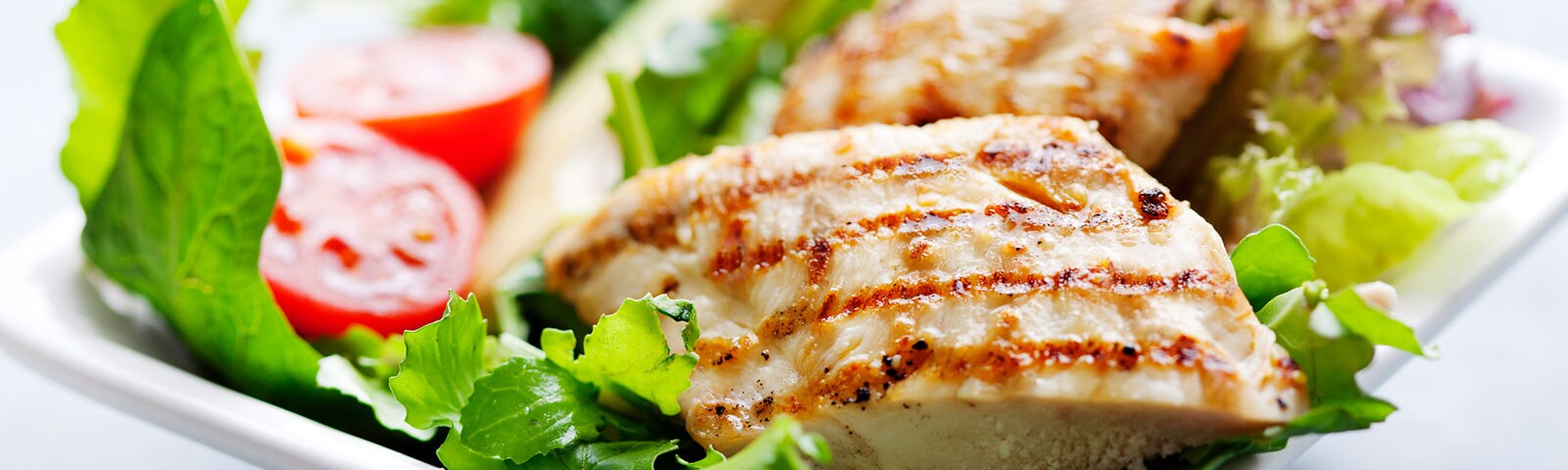 Cooked chicken breast on a bed of greens