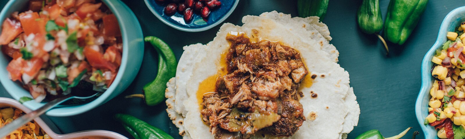 Tacos and corn salsa and pico de gallo on a wooden table