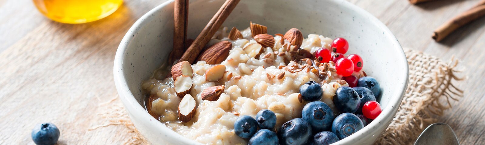 a bowl of oatmeal with almonds, blueberries and sticks of cinnamon a bowl of oatmeal with almonds, blueberries and sticks of cinnamon