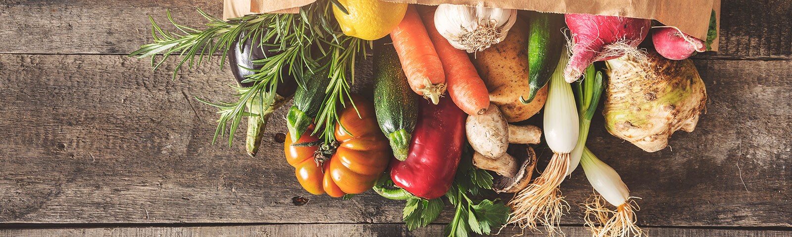 Fresh produce is a browl paper bag on a wooden table Fresh produce is a browl paper bag on a wooden table