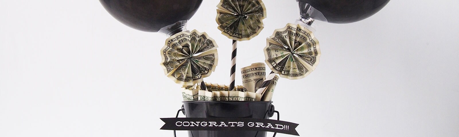 Black balloons above a small bucket with money that's shaped into accordion stars