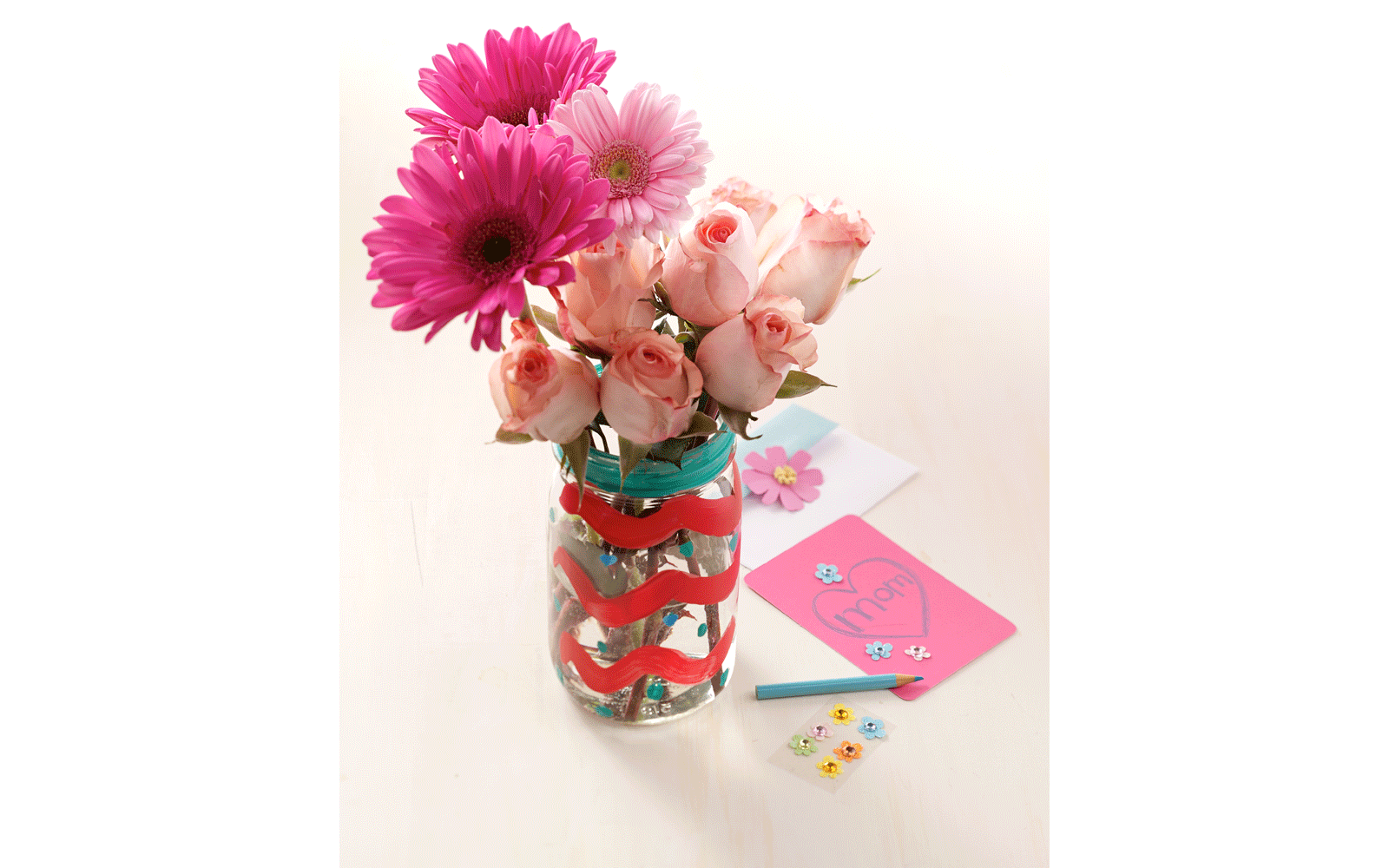 Decorated with pink ribbon around a mason jar filled with roses Decorated with pink ribbon around a mason jar filled with roses