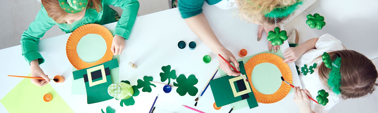 Kids painting on a white table of St. Patricks decor