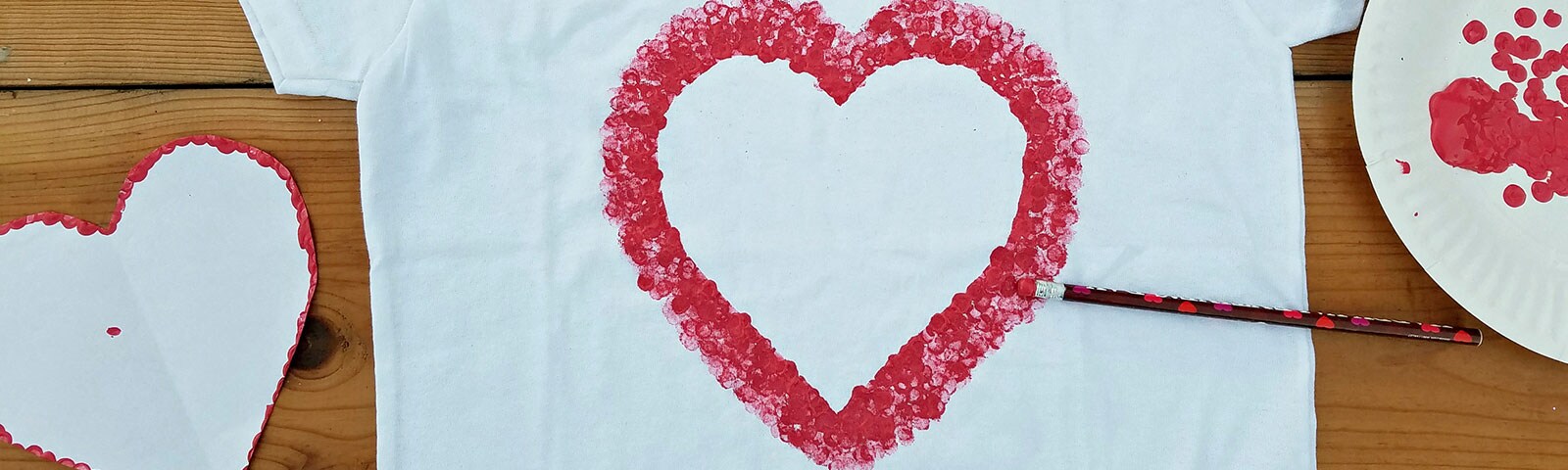 White t-shirt laid flat on the floor with a DIY stamped red outline of a heart in the middle White t-shirt laid flat on the floor with a DIY stamped red outline of a heart in the middle