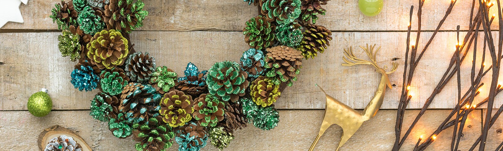A large pinecone wreath dusted in glitter of various colors sitting on a rustic wooden table A large pinecone wreath dusted in glitter of various colors sitting on a rustic wooden table