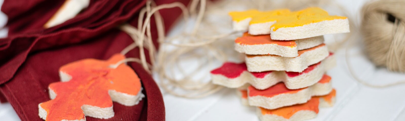 Homemade ornaments on a white table in the shape of leaves painted different shades of red, orange and yellow. Homemade ornaments on a white table in the shape of leaves painted different shades of red, orange and yellow.