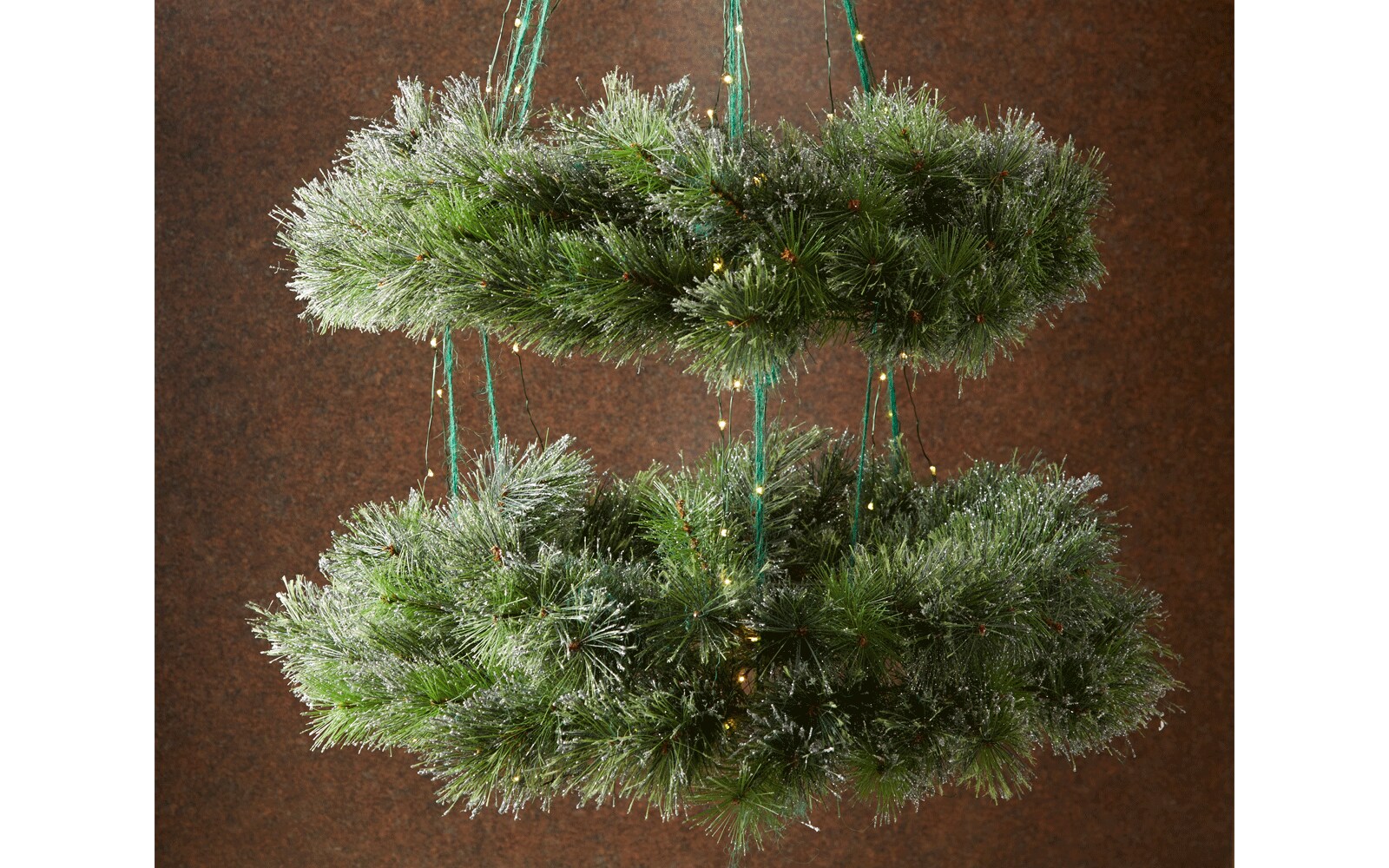 Two wreaths hanging as a chandelier by green ribbon and wrapped in Christmas lights Two wreaths hanging as a chandelier by green ribbon and wrapped in Christmas lights