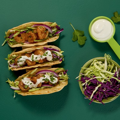 Three zesty shrimp soft tacos, with cabbage, lettuce, cilantro and topped with sour cream.